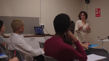 Üniversite konferans salonunda çeşitli kolej öğrencilerine ders veren kadın profesör. Dikkatli öğrenciler bir ders dinliyorlar.