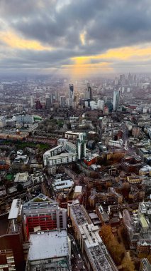 Londra şehir manzarası, gün batımında panoramik hava manzarası, şehir binaları ve mimarisi üzerinde dramatik bulutları aşan güneş ışınları.