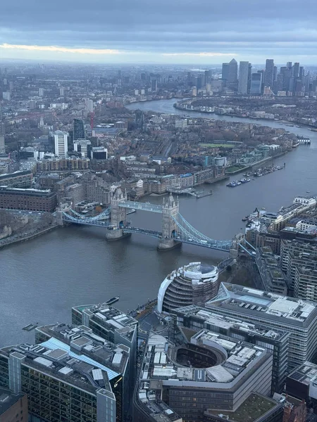 Londra 'nın Thames nehri üzerindeki hava manzarası, kule köprüsü ve bulutlu bir gökyüzü altında kentsel gelişim.