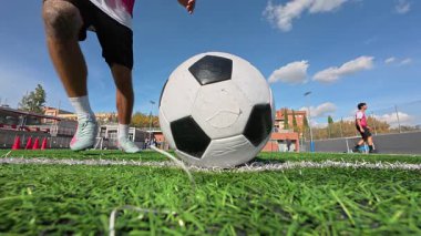 Bir futbolcunun saha sahasında topa vurduğu düşük açılı perspektif. Sporcu antrenman sırasında güçlü bir atış yapar.