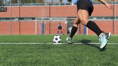 Kadın bir futbolcunun penaltı vuruşunu yavaş çekimde izlemek. Kaleci dalıyor ama topu kaleye girmekten kurtaramıyor.