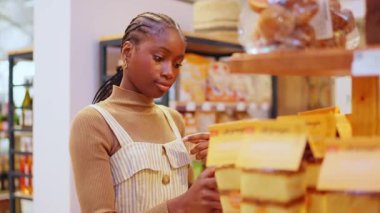 Thoughtful young woman carefully reading the ingredients on a product package. Customer choosing healthy food in a grocery store