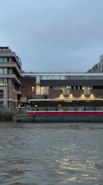 Thames nehri boyunca Londonlar 'ın güney kıyısı mimarisi manzarasıyla dolaşırken, alacakaranlıktaki tarihi güney köprüsünün altından geçerken.