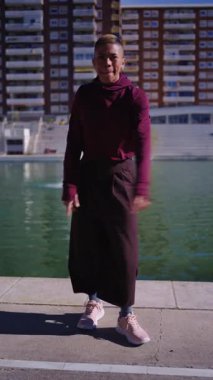 Şehir parkında dans figürleri sergileyen sakallı, enerjik bir genç. Özgürlüğünü ve neşesini ifade eden modern dansçı