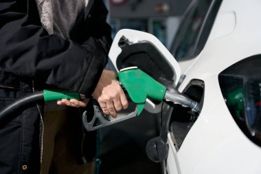 Yeşil yakıt pompası hortumunu tutan insanlar, benzin istasyonundaki beyaz araba deposuna yerleştiriyorlar - fiyat artışı - benzin krizi