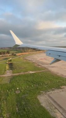 Uçak inerken kanat ve kanatlarını gösteren bir uçak penceresinden yolcuların bakış açısı ve uçak pistte seyahat ediyor.