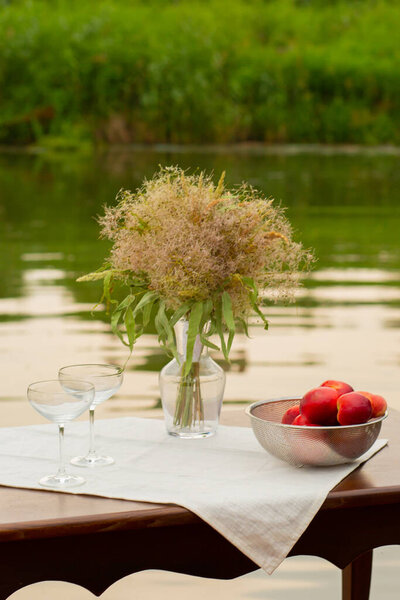 two glasses on the background of the lake sunset stand on the table fruits in a bowl, beautiful background