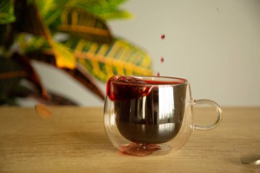 Bir bardak bardakta amber çayı. Masada çiçek ve natura.