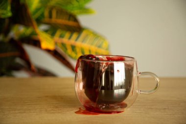 Bir bardak bardakta amber çayı. Masada çiçek ve natura.