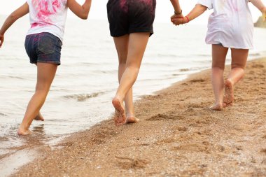 Çocuklar plaj boyunca koşar, deniz kenarında, güzel gün batımı, çocukların ayakları