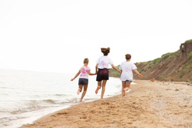 Çocuklar plaj boyunca koşar, deniz kenarında, güzel gün batımı, çocukların ayakları