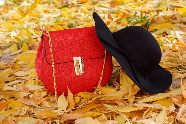 Red fashionable handbag and black hat with wide brim — Stock Photo, Image