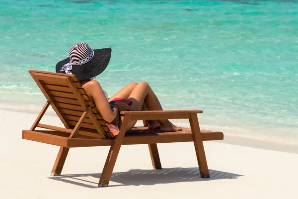 Young woman sunbathing on lounger at tropical beach — Stock Photo, Image