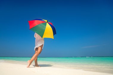 Kumlu sahilde renkli bir şemsiye ile kız