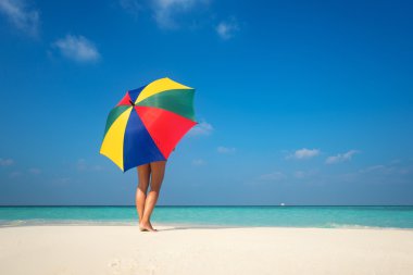 Kumlu sahilde renkli bir şemsiye ile kız