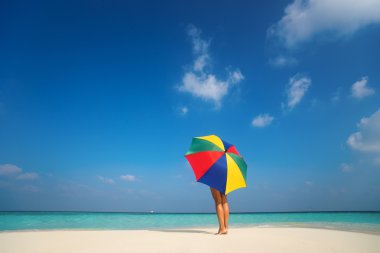 Kumlu sahilde renkli bir şemsiye ile kız