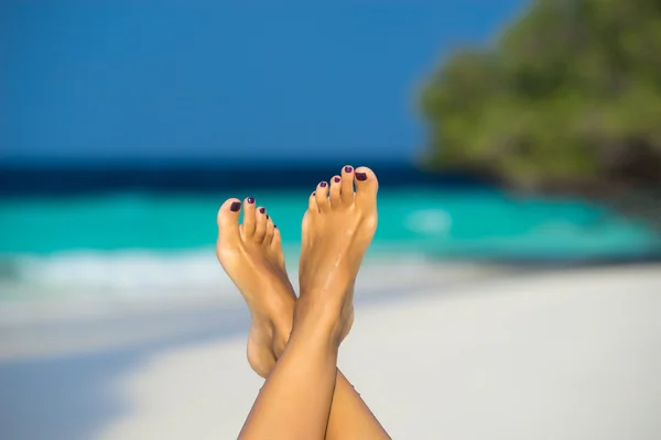 女性的脚在热带海滩上蓝色的海水中的特写镜头. — 图库照片