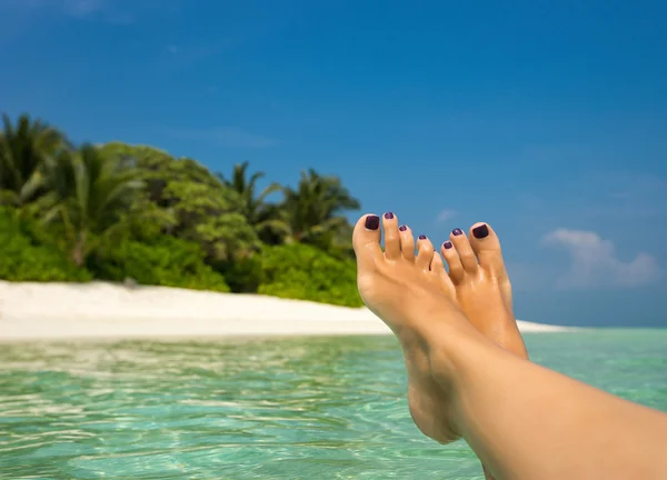Közelkép a trópusi tengerparton kék vízben női láb. — Stock Fotó