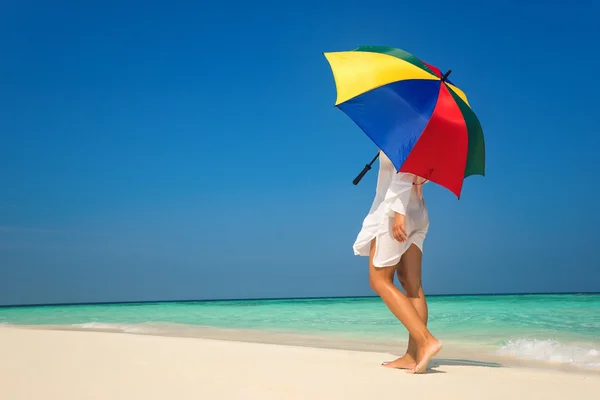 Menina com um guarda-chuva colorido na praia de areia — Fotografia de Stock