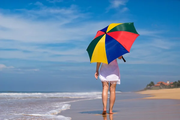 Meisje met een kleurrijke paraplu op het zandstrand — Stockfoto