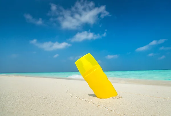 Garrafa de creme protetor solar na praia — Fotografia de Stock