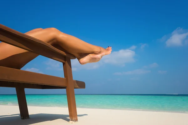 在躺椅上晒日光浴的年轻女人。双腿. — 图库照片