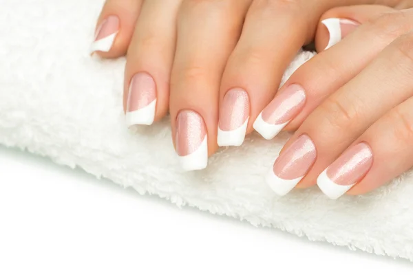 Beautiful fingers with french manicure on the towel. Manicure in — Stock Photo, Image