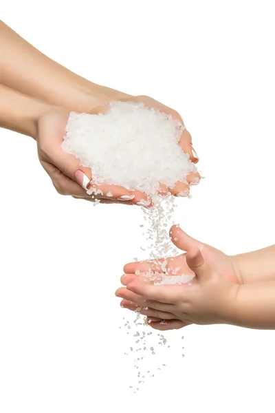 Zee zoutkristallen in vrouwen en kinderen hand. — Stockfoto