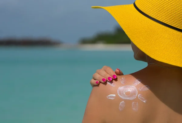 Frau mit sonnenförmiger Sonnencreme am Strand — Stockfoto