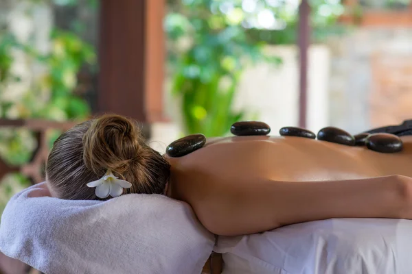 Mujer joven recibiendo masaje de piedra caliente en el salón de spa. Belleza tratar — Foto de Stock