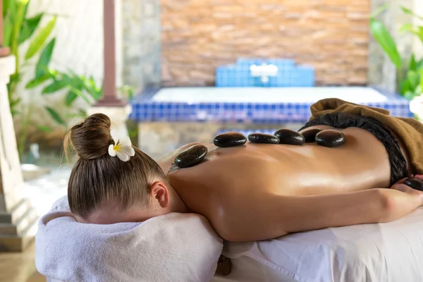 Young woman getting hot stone massage in spa salon. Beauty treat — Stock Photo, Image