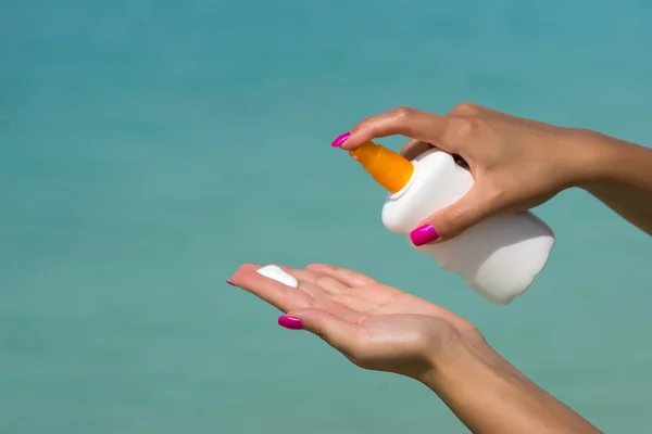 Vrouw handen zetten zonnebrandcrème uit een zonnebrandfles — Stockfoto