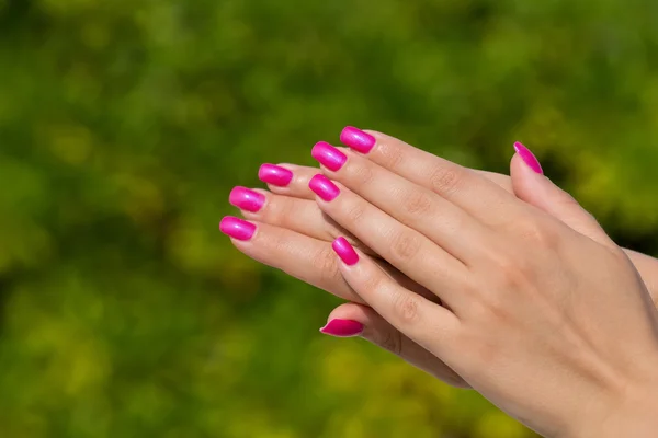 Mãos de mulher com unhas rosa manicured closeup. Carro de pele e unhas — Fotografia de Stock