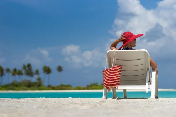 Young woman sunbathing on lounger at tropical beach — Stock Photo, Image