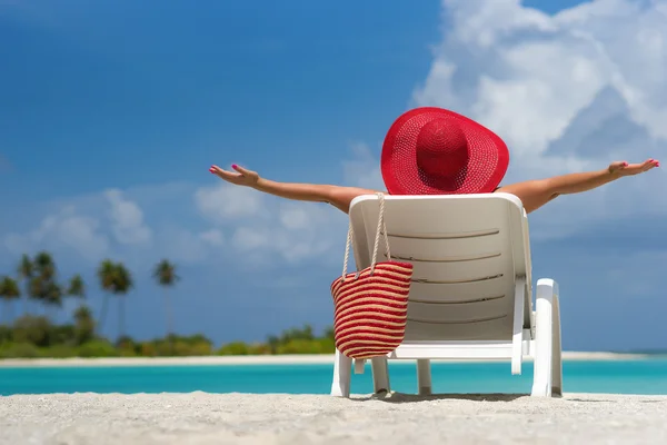 Mujer joven tomando el sol en una tumbona en la playa tropical — Foto de Stock