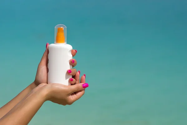 Mãos de mulher pondo protetor solar de uma garrafa de creme solar — Fotografia de Stock