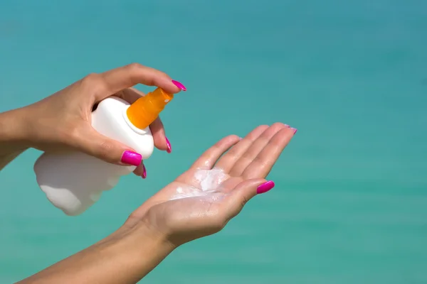 Mujer manos poniendo protector solar de una botella de crema solar —  Fotos de Stock