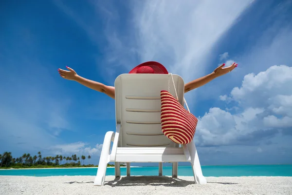 Young woman sunbathing on lounger at tropical beach — Stock Photo, Image