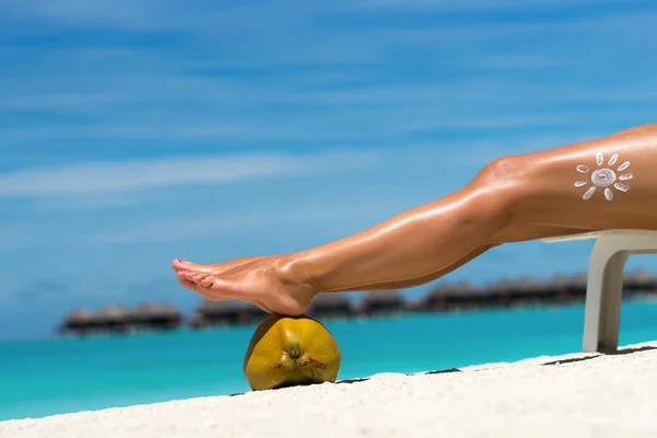 Mooie benen van de vrouw op kokosnoot op het strand, blauwe zee backgro — Stockfoto