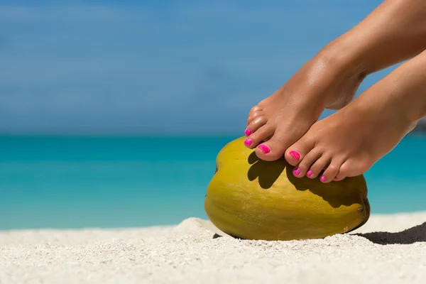 Piękne nogi kobiet na kokos na plaży, błękitne morze backgro — Zdjęcie stockowe