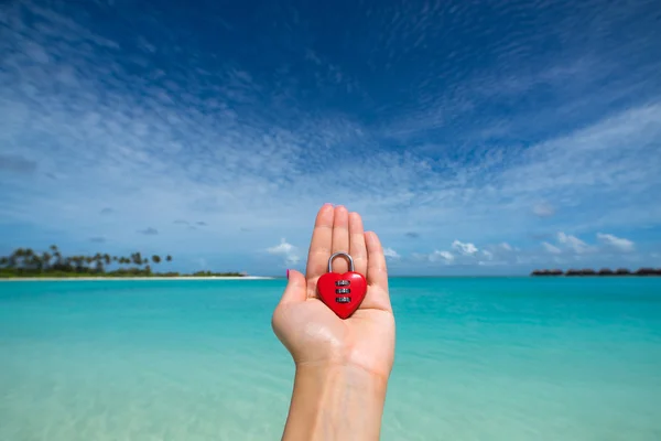 Rood hart met een slot op tropisch strand in de hand van de vrouw — Stockfoto