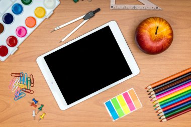 okul malzemeleri ve yukarıdan gelen ahşap okul masasında tablet