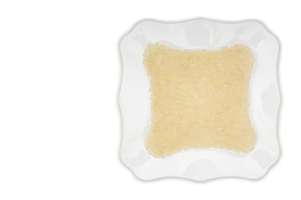Riz blanc long sur fond blanc, céréales crues non cuites, macro sur l'assiette — Photo
