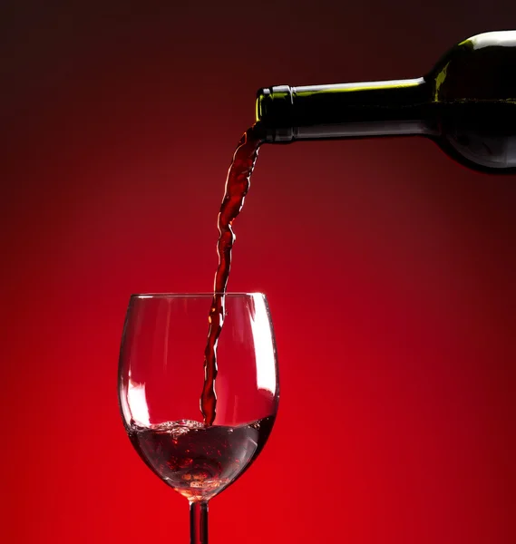 Vinho tinto sendo derramado em copo de vinho — Fotografia de Stock