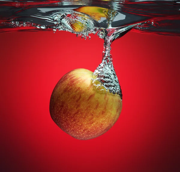 Red apple splashing into water — Stock Photo, Image