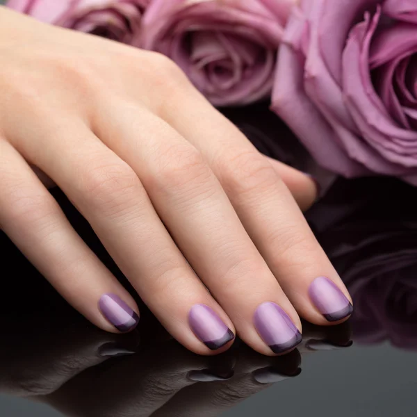 Hermosa manicura, el pulido es un color violeta. Fondo de flores . —  Fotos de Stock