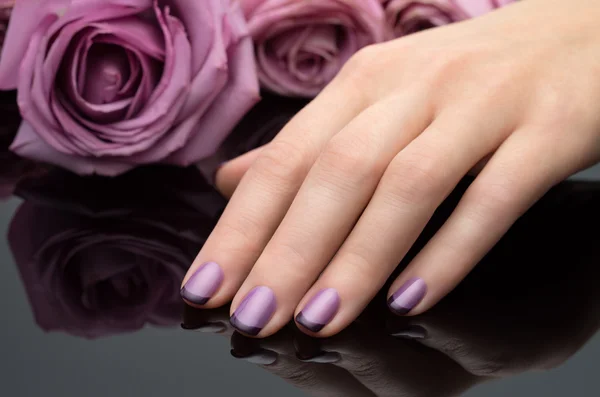 Beautiful manicure, polish is a violet color. Flower background. — Stock Photo, Image