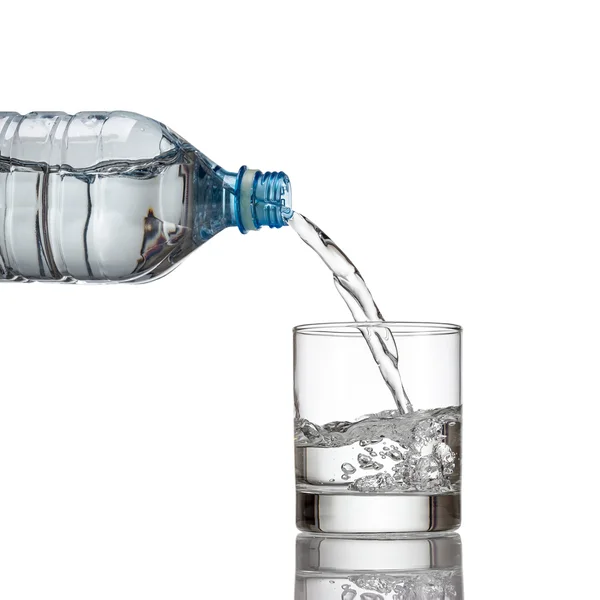 Zimna woda butelki wlać wody do szkła na białym tle — Zdjęcie stockowe