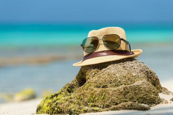 Straw hat, towel beach sun glasses and flip flops on a tropical — Stock Photo, Image