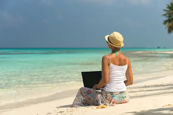 Kvinne på tropisk strand med bærbar datamaskin – stockfoto